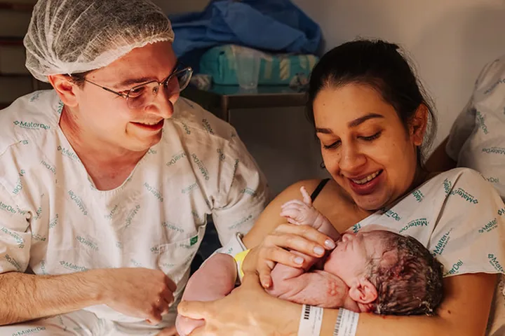 Família sorri com o bebê no colo após o nascimento